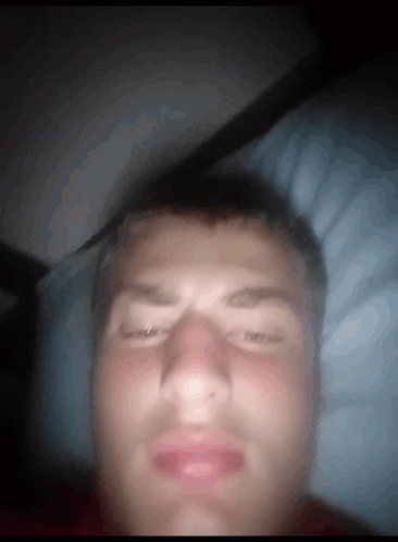 A Man Laying In Bed With His Eyes Closed And His Mouth Open GIF