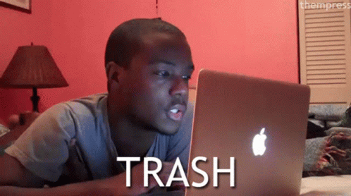 A Man Laying On A Bed Looking At A Laptop With The Word Trash Written On The Screen GIF