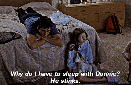 A Man Laying On A Bed Next To A Girl With The Words Why Do I Have To Sleep With Donnie GIF
