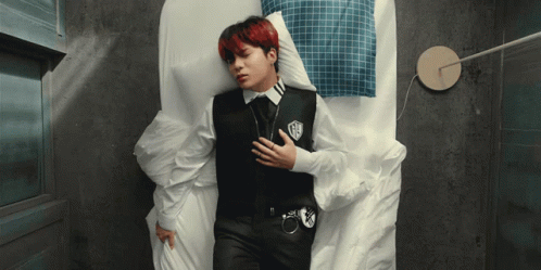A Man Laying On A Bed With His Hand On His Chest GIF