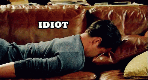 A Man Laying On A Brown Leather Couch With The Word Idiot Above Him GIF