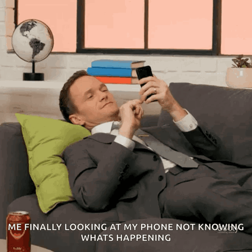A Man Laying On A Couch Looking At His Phone GIF