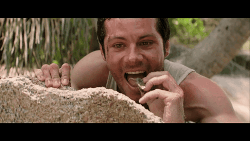 a man laying on a rock eating something