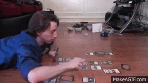 A Man Laying On The Floor Playing A Game Of Cards GIF