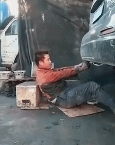 A Man Laying On The Ground Working On A Car With A License Plate That Says ' A ' On It GIF