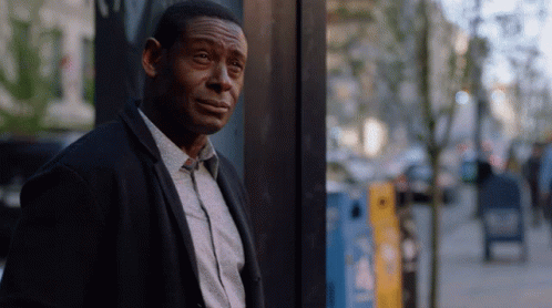 A Man Leaning Against A Wall With A Yellow Box In The Background That Says ' A ' On It GIF