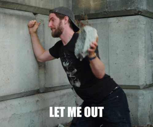 A Man Leaning Against A Wall With The Words Let Me Out Written On The Bottom GIF