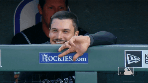 A Man Leaning Over A Rockies.com Sign GIF