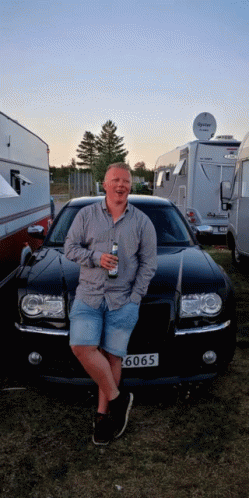 A Man Leans Against A Black Car With A License Plate That Says ' 6060 ' GIF