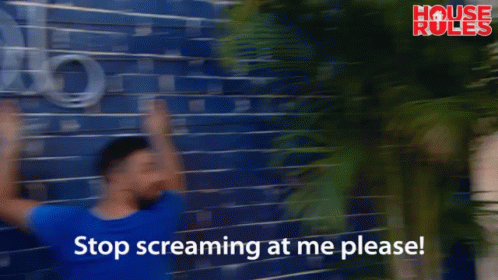 A Man Leans Against A Blue Brick Wall With The Words Stop Screaming At Me Please On The Bottom GIF
