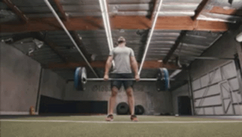 A Man Lifting A Barbell In A Gym GIF