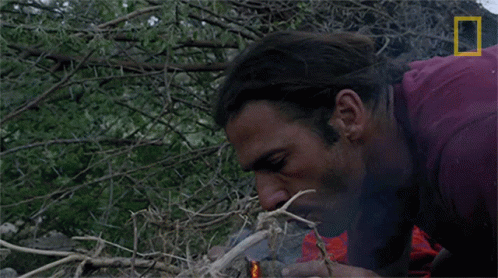 A Man Lighting A Fire With A National Geographic Logo In The Corner GIF