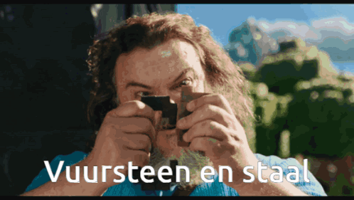 A Man Looking Through A Magnifying Glass With The Words Vuursteen En Staal Written Below Him GIF