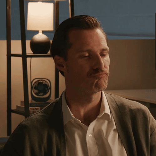 A Man Making A Face In Front Of A Lamp And A Fan GIF