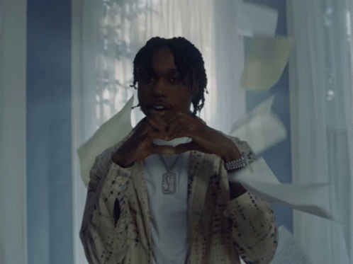 a man making a heart shape with his hands and a necklace with the letter f on it