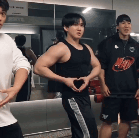A Man Making A Heart Shape With His Hands In Front Of A Mirror In A Gym GIF