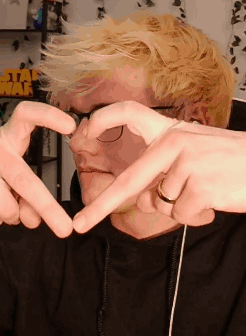 A Man Making A Heart Shape With His Hands In Front Of A Sign That Says Star Wars GIF