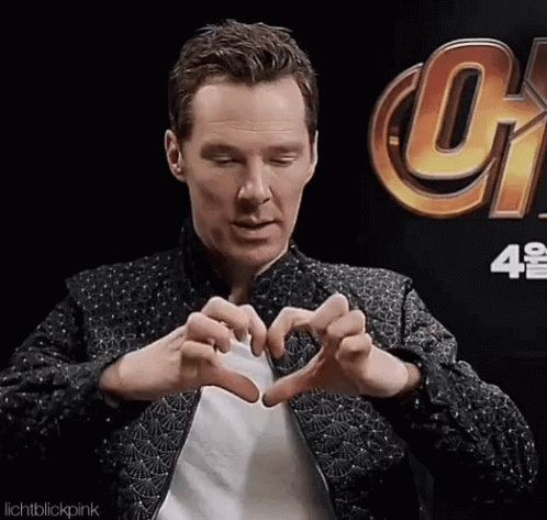 A Man Making A Heart With His Hands In Front Of A Sign That Says Infinity War GIF