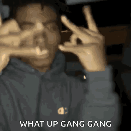 A Man Making A Peace Sign With The Words " What Up Gang Gang " Written Below Him GIF
