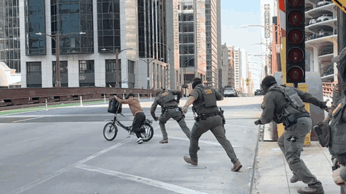 A Man On A Bike Is Being Chased By Police Officers GIF