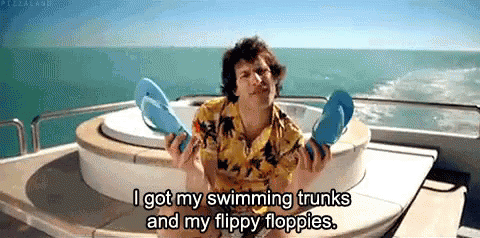 A Man On A Boat Holding Flip Flops And Saying I Got My Swimming Trunks And My Flippy Floppies . GIF