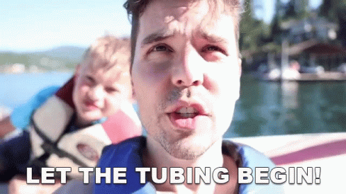 A Man On A Boat With The Words Let The Tubing Begin Below Him GIF