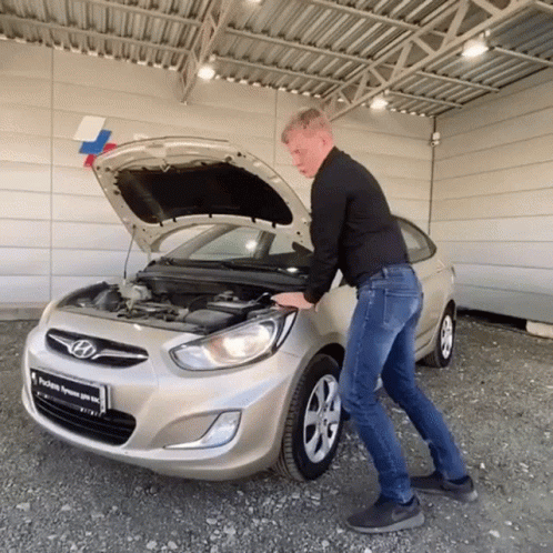A Man Opens The Hood Of A Silver Hyundai GIF