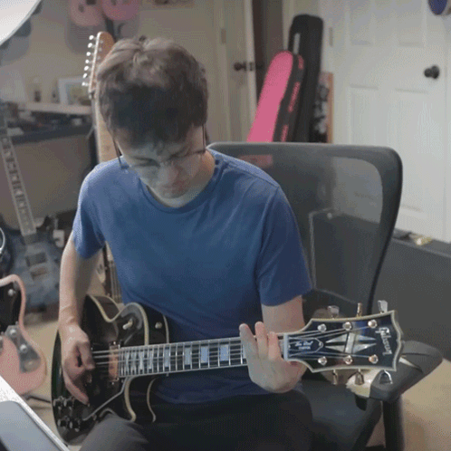 a man playing a gibson guitar in a chair