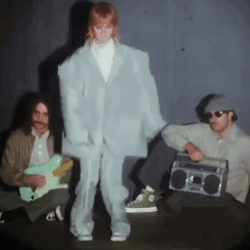 A Man Playing A Guitar And A Man Holding A Boom Box GIF