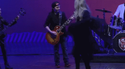 A Man Playing A Guitar And A Woman Singing On A Stage GIF