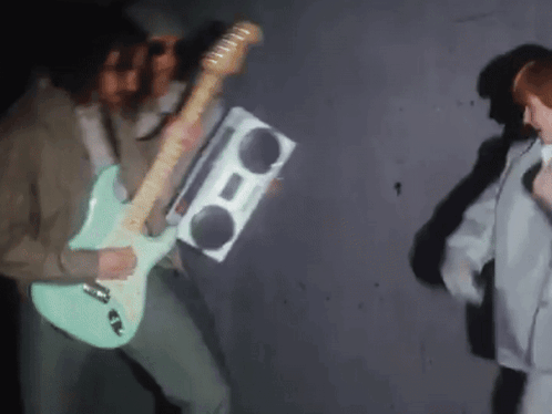 A Man Playing A Guitar And Holding A Boom Box GIF
