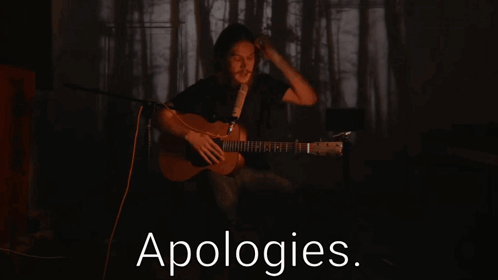 Man Playing Guitar Singing Into Microphone With Apologies Text GIF