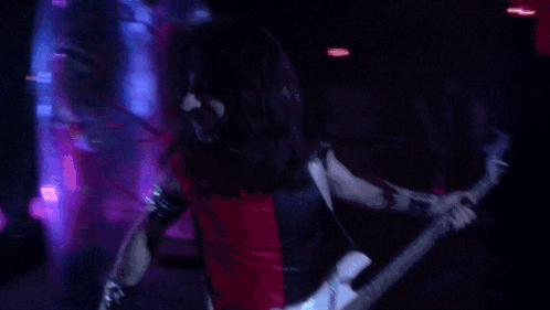 A Man Playing A Guitar In A Dark Room GIF