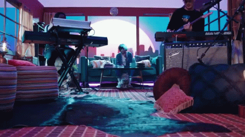 A Man Playing A Guitar In A Living Room With A Fender Amplifier GIF