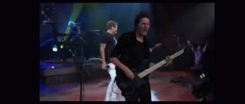a man playing a guitar in front of a group of people