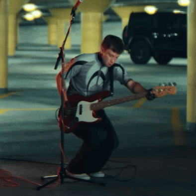 A Man Playing A Guitar In Front Of A Microphone GIF