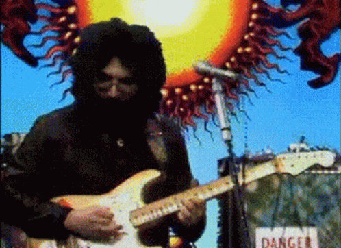 A Man Playing A Guitar In Front Of A Sign That Reads Danger GIF