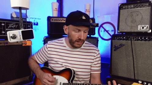 A Man Playing A Guitar In Front Of An Amp That Says Roz GIF
