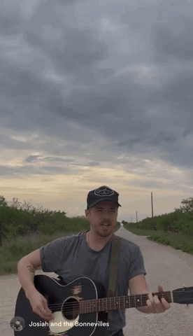 A Man Playing A Guitar On A Dirt Road With The Name Josiah And The Bonnevilles Written Below Him GIF