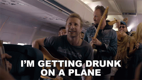 A Man Playing A Guitar On A Plane With The Words " I 'M Getting Drunk On A Plane " GIF