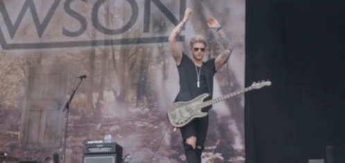 A Man Playing A Guitar On A Stage In Front Of A Sign That Says Wson GIF