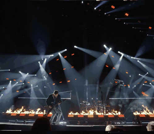 A Man Playing A Guitar On A Stage Surrounded By Fire GIF