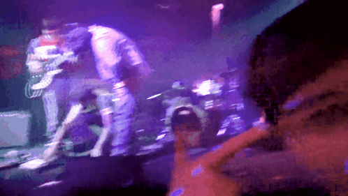 A Man Playing A Guitar On A Stage With Purple Lights GIF