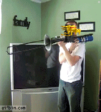 A Man Playing A Trombone In Front Of A Tv With A Family Sign On The Wall GIF