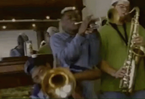 A Man Playing A Trumpet And Another Man Playing A Saxophone In Front Of A Mirror GIF