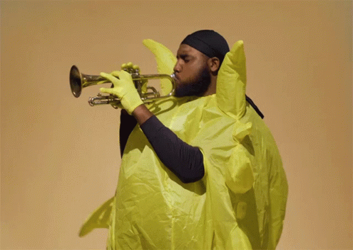 A Man Playing A Trumpet In A Yellow Outfit GIF
