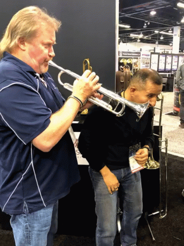 A Man Playing A Trumpet Next To Another Man GIF