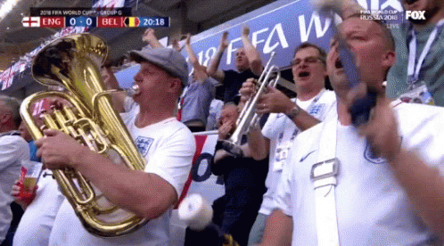 A Man Playing A Tuba In Front Of A Sign That Says Fifa World Cup GIF