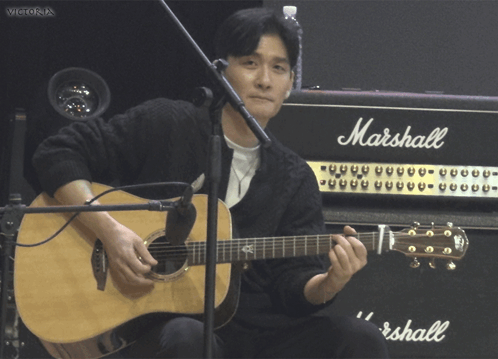 A Man Playing An Acoustic Guitar In Front Of A Marshall Amplifier GIF