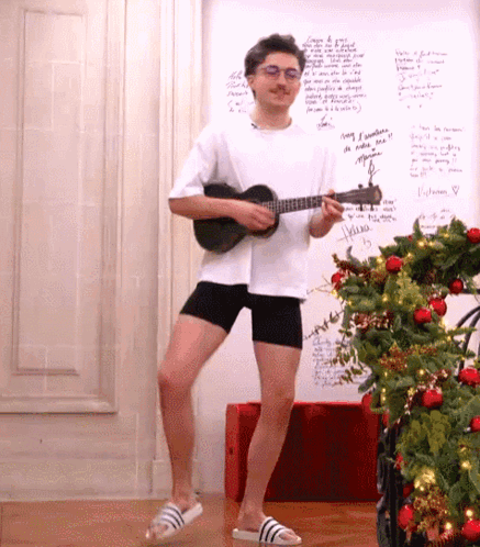 Man Playing Ukulele In Front Of Christmas Tree GIF